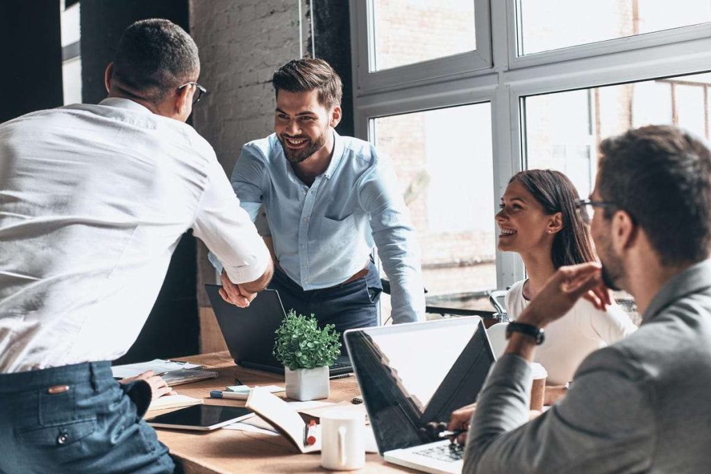 Two employees shake hands during meeting during a moment of collaboration