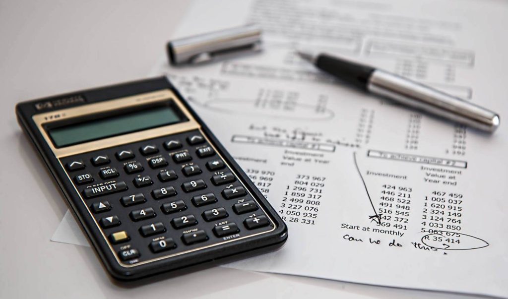 Calculator on top of pen and document used to work out company costs and savings