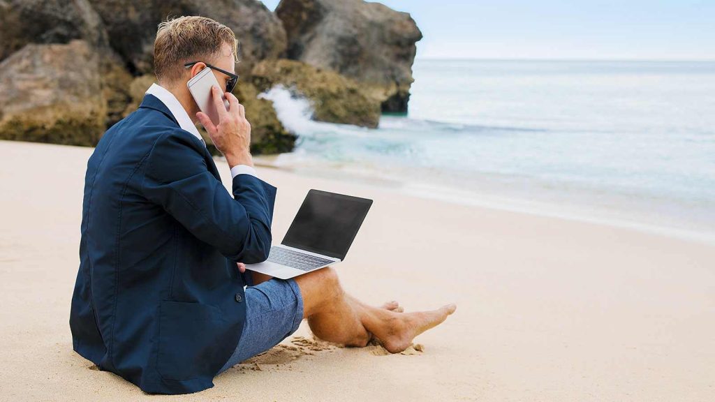Remote work employee sits on beach with laptop demonstrating the benefits of mobile devices in business