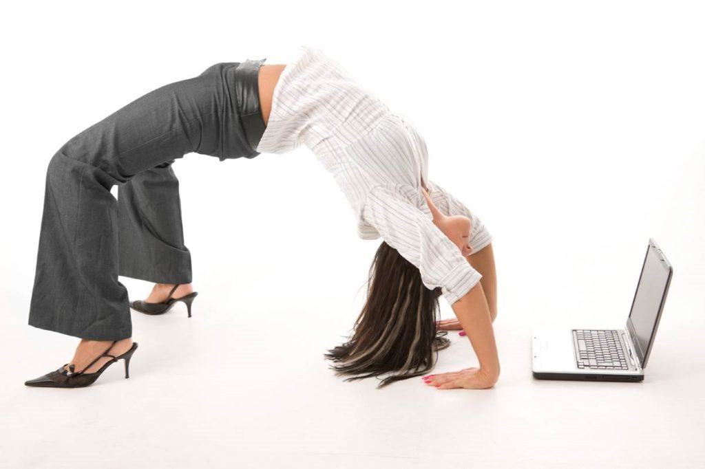 Company worker stretches next to laptop to demonstrate employee flexibility and mobile devices in business