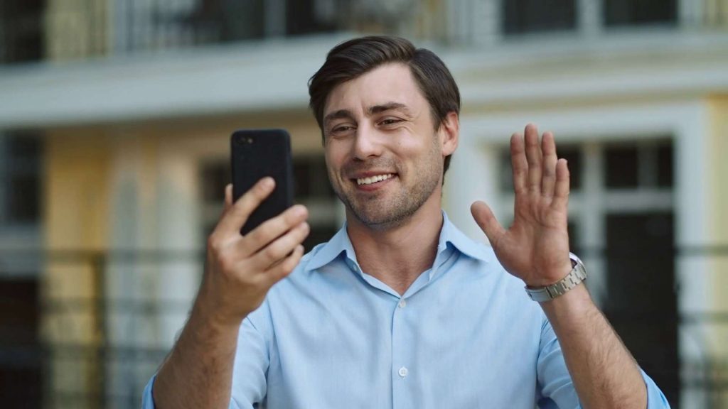 Employee using business mobile phone plan talks to and waves at team outside of office