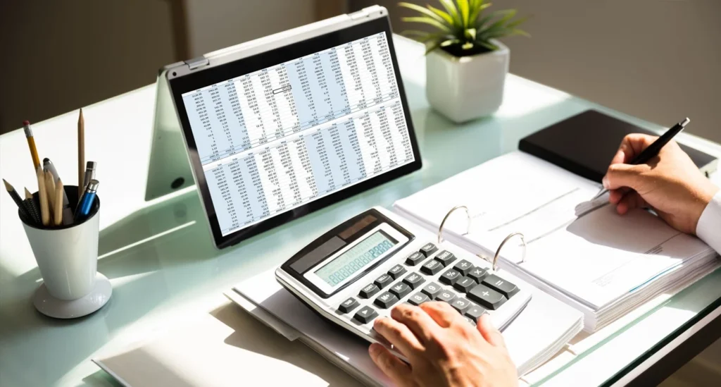 Calculating how to reduce business costs in 2024 with stack of coins and calculator