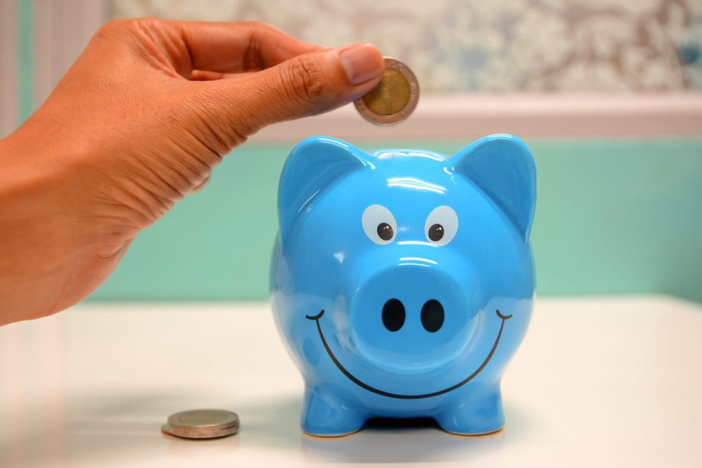 Person places 2 Euro coin into blue piggy bank