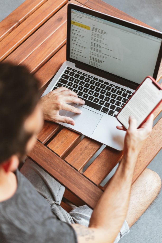 Man checks his emails and smartphone for emails going into spam