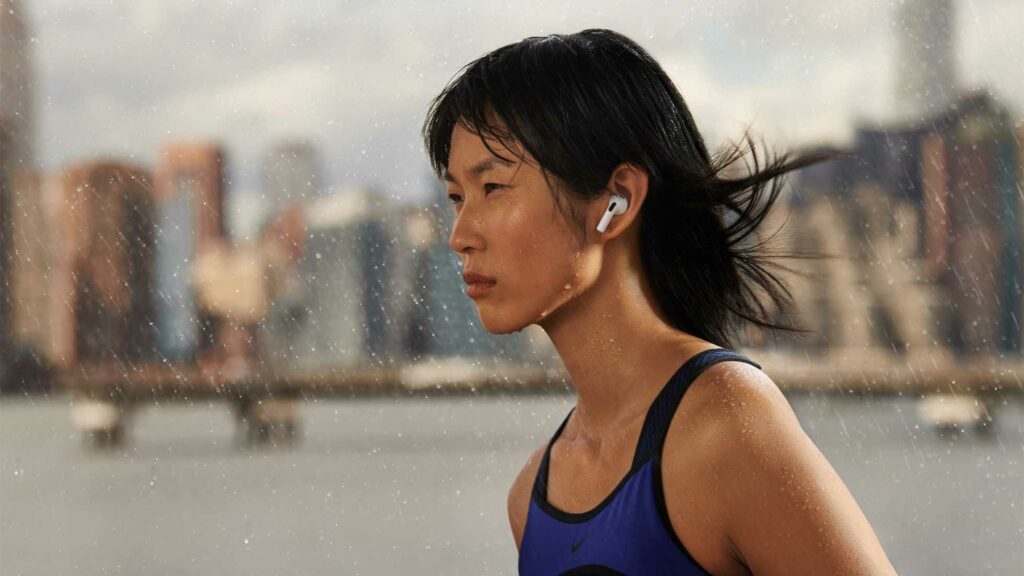 Athletic woman runs in rain with AirPod Pros wireless earphones