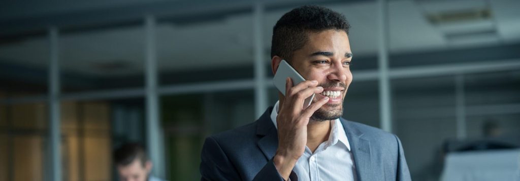 Smiling employee uses a business mobile phone to talk to client in the office