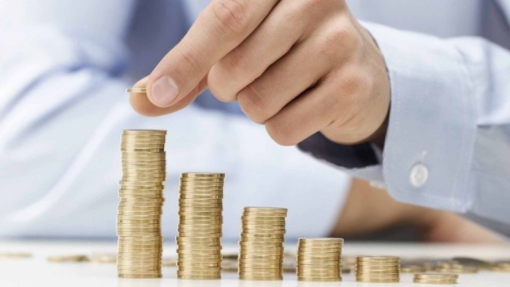 Man in shirt stacks up pound coins into several piles using savings from a business SIM only plan