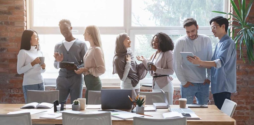 Group of happy employees standing by desk collaborate together  