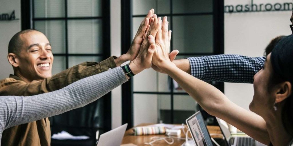 Group of happy workers high fiving in the office