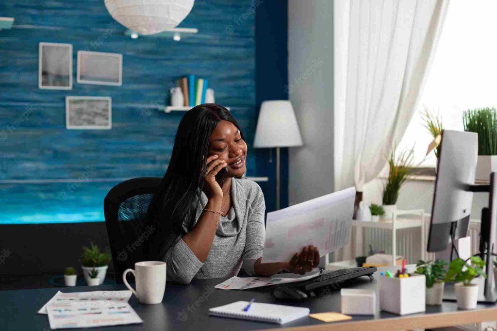 Office worker sits at desk talking to client over business mobile phone