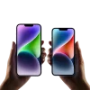 Two hands hold up iPhone 14 and 14 Plus smartphone models for size comparison
