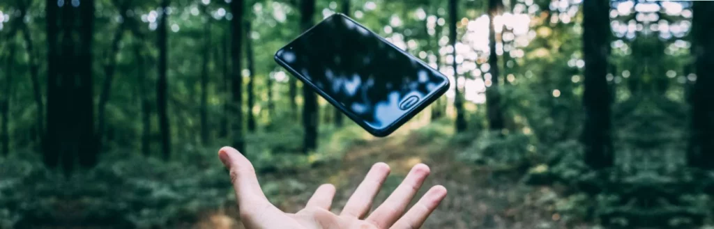 Outstretched hand ready to mid-air smartphone in the forest