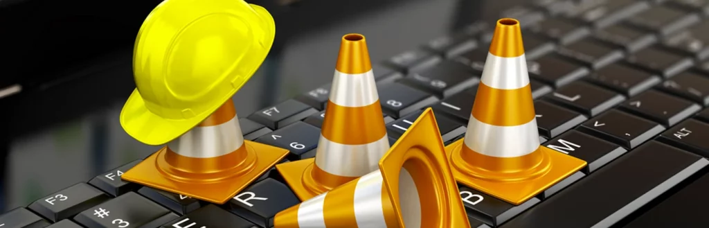 Traffic cones and hard hat sit atop keyboard in an office to signify broadband network downtime