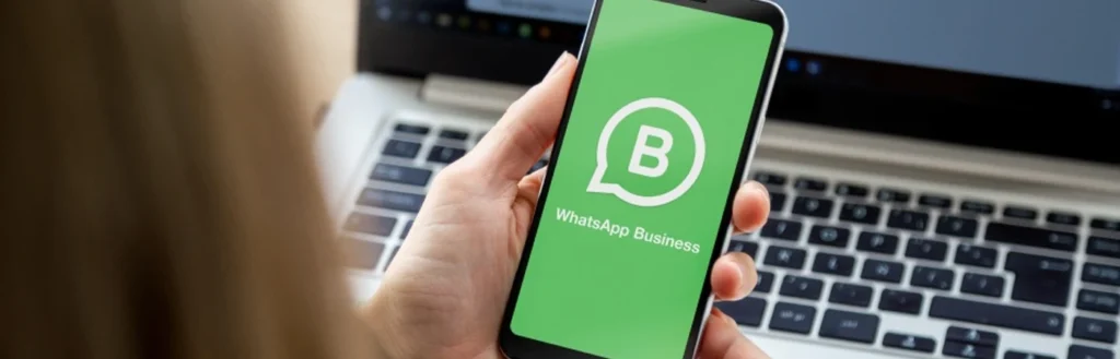 Woman near laptop uses Whatsapp for business on her mobile phone