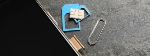 Nano-SIM, adapters and ejector tool beside smartphone – switching physical SIMs vs using a multi-network SIM